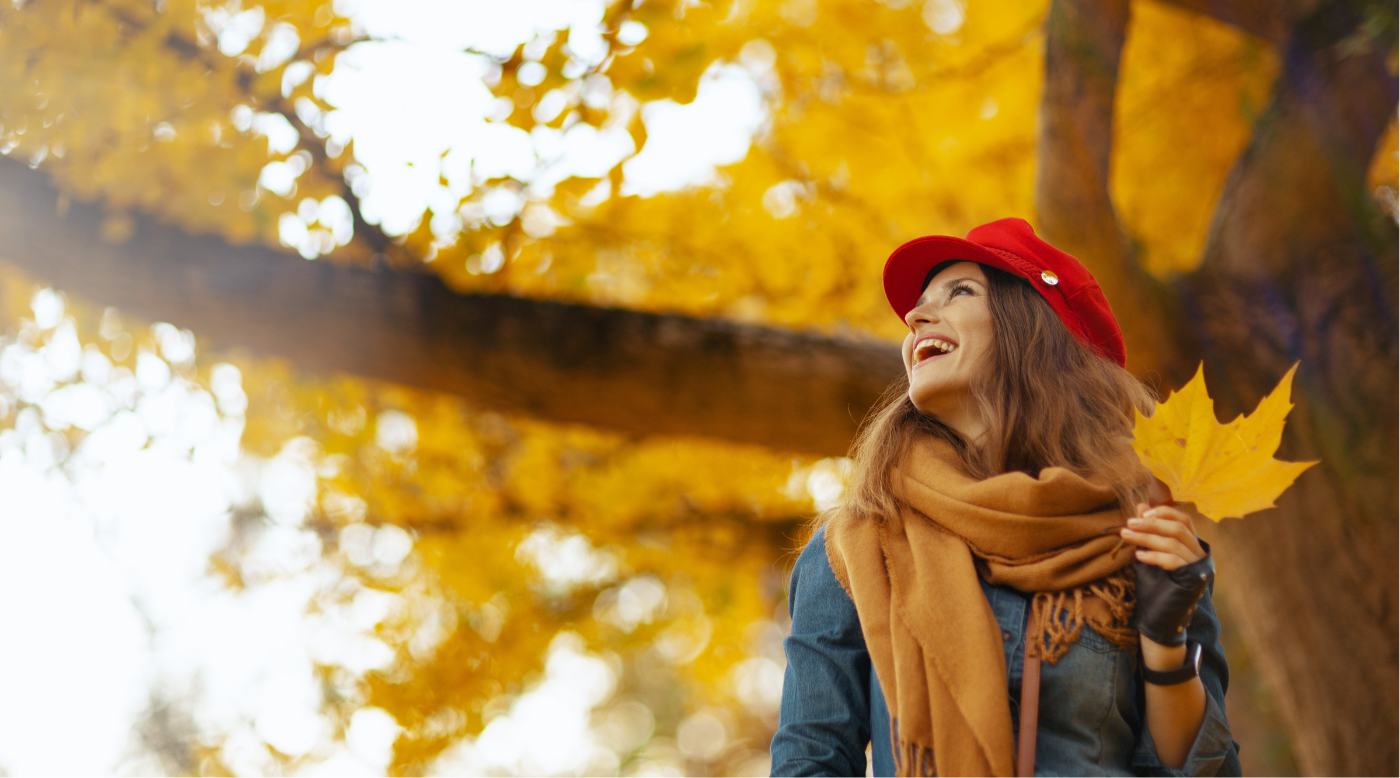 •	Frau mit warmer Herbstjacke lächelt beim Spaziergang